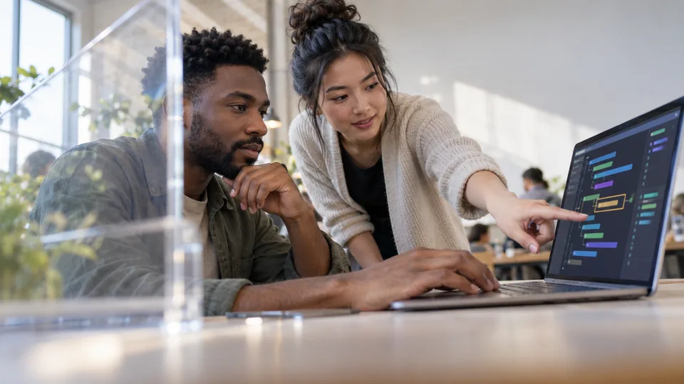 Two learners solve a coding exercise together at a laptop.