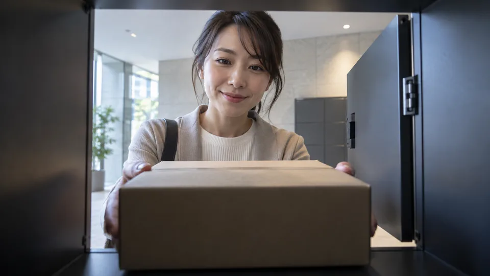 A young resident retrieves a plain parcel from an apartment locker in a quiet shared entrance.