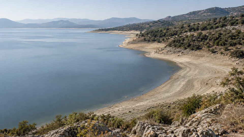 A broad pale sediment band between lake water and higher vegetation reveals a period of low water.